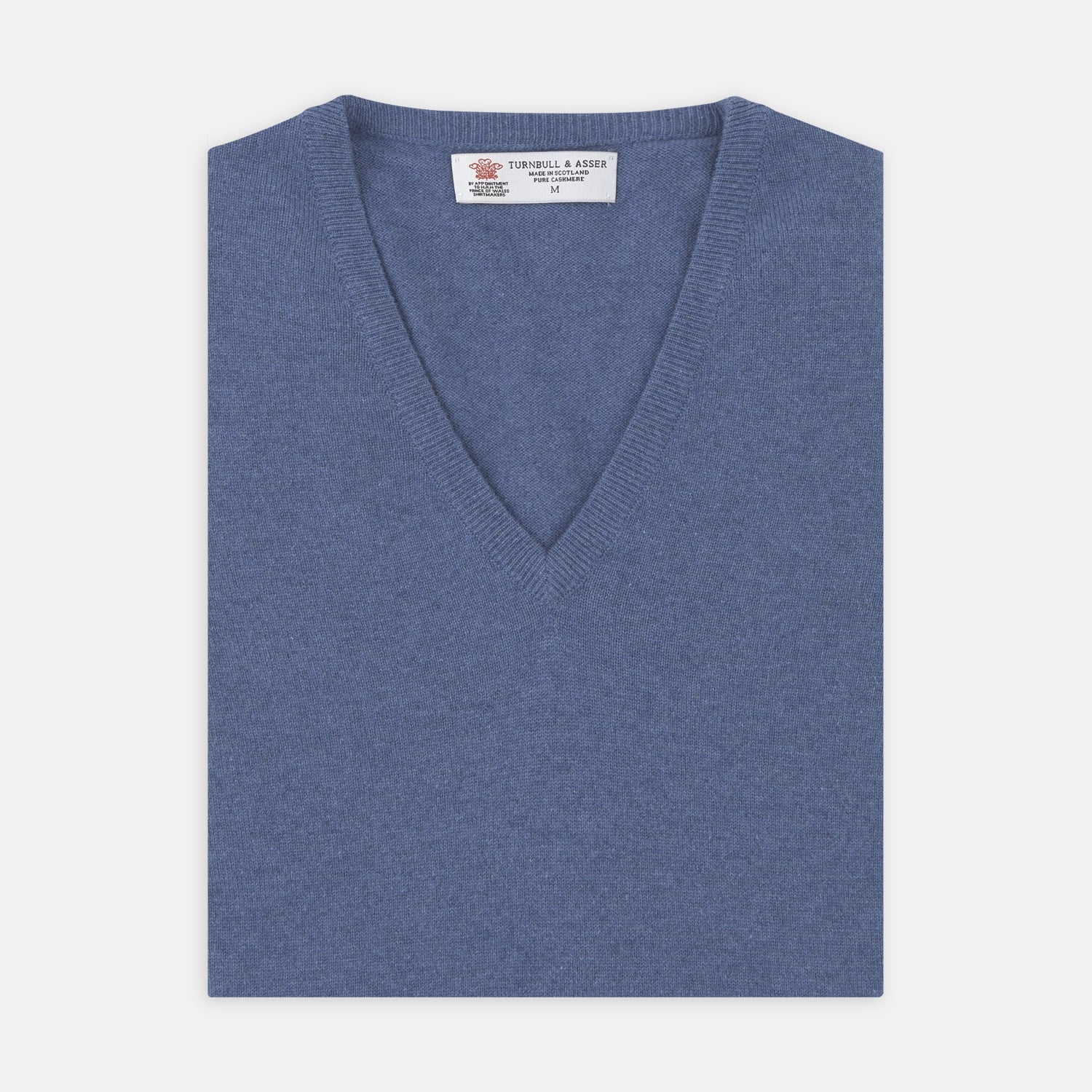 View 1 of product The Turnbull & Asser Blue V-Neck Cashmere Slipover, neatly folded with the label visible, is crafted from soft cashmere and ideal for formal layering. Shown against a white background.