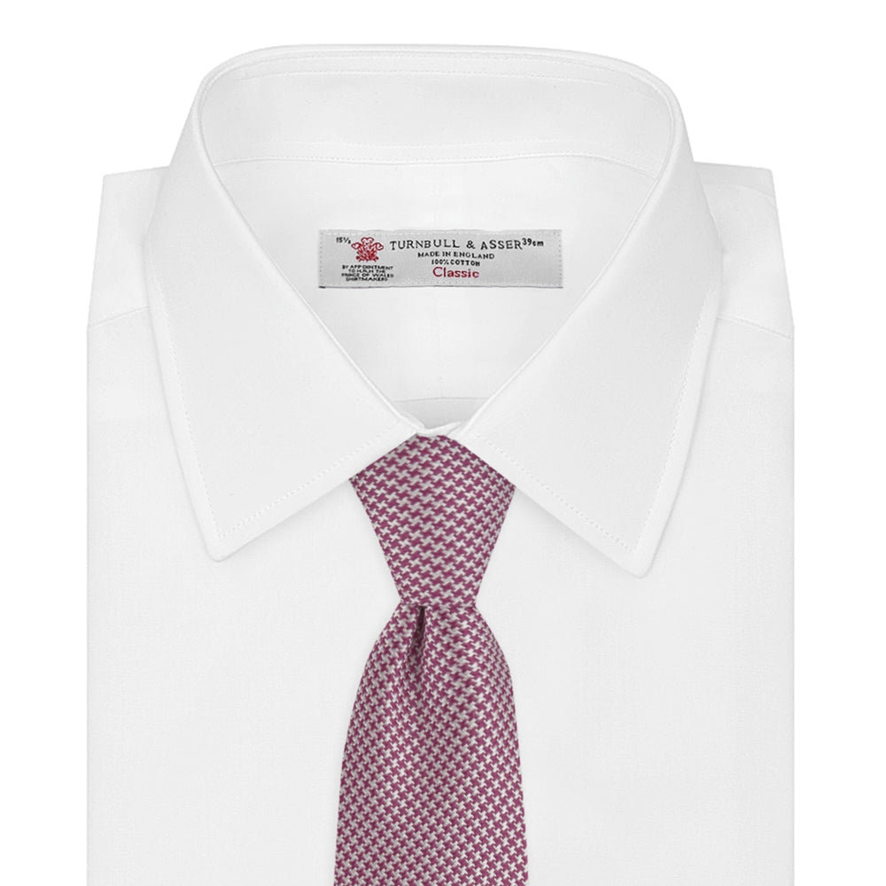 The Turnbull & Asser Dark Pink Houndstooth Silk Tie is rolled up and displayed on a plain white background.