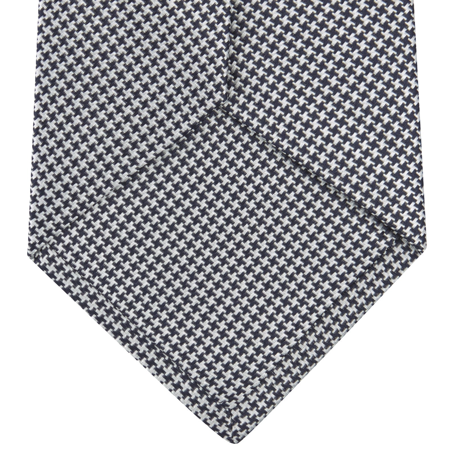 View 4 of product The Turnbull & Asser Navy Houndstooth Silk Tie features a refined small houndstooth pattern in navy, elegantly rolled and showcased on a white background.