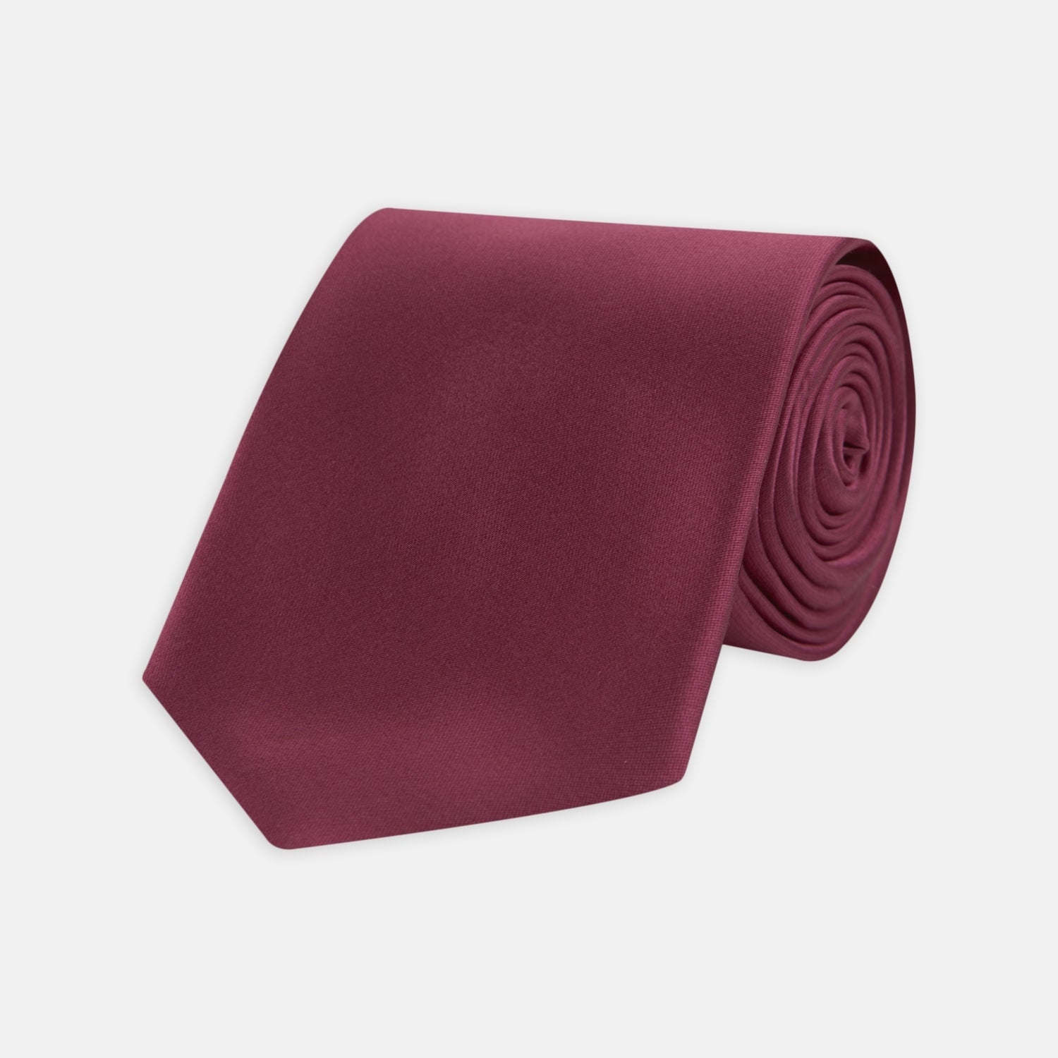 View 1 of product A Turnbull & Asser Dark Pink Plain Satin Silk Tie, crafted from satin silk, is rolled up and displayed on a plain white background.