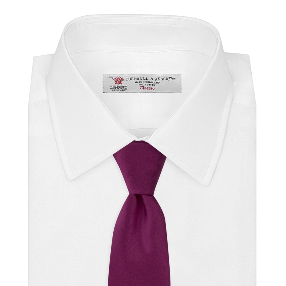 A Turnbull & Asser Dark Pink Plain Satin Silk Tie, crafted from satin silk, is rolled up and displayed on a plain white background.