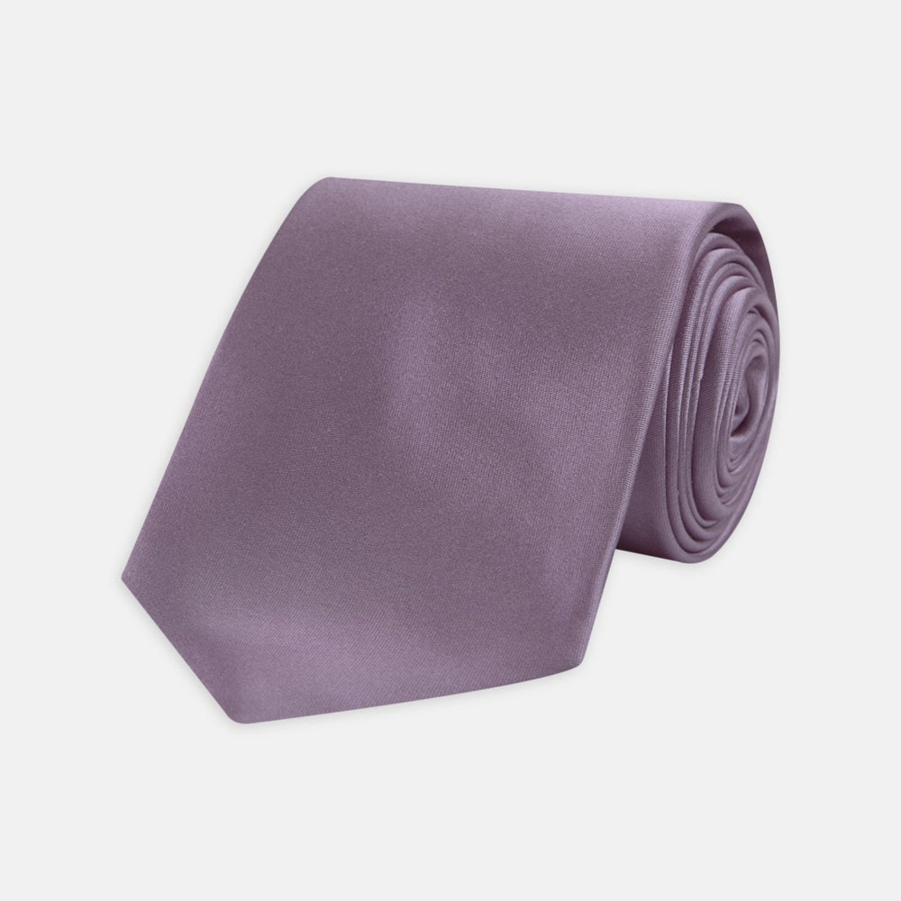 The Turnbull & Asser Lilac Plain Satin Silk Tie, featuring a smooth finish, is neatly rolled and displayed on a white background—a classic accessory for any versatile wardrobe.