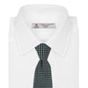 View 2 of product The Turnbull & Asser Forest Green and White Diamond Silk Tie features a geometric pattern of small, evenly spaced white diamonds on a forest green background, displayed rolled up on a white surface.
