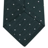 View 4 of product The Forest Green and White Small Spot Herringbone Silk Tie by Turnbull & Asser features a dark green woven herringbone pattern with small white spots, crafted from fine English silk and shown rolled up on a white background.
