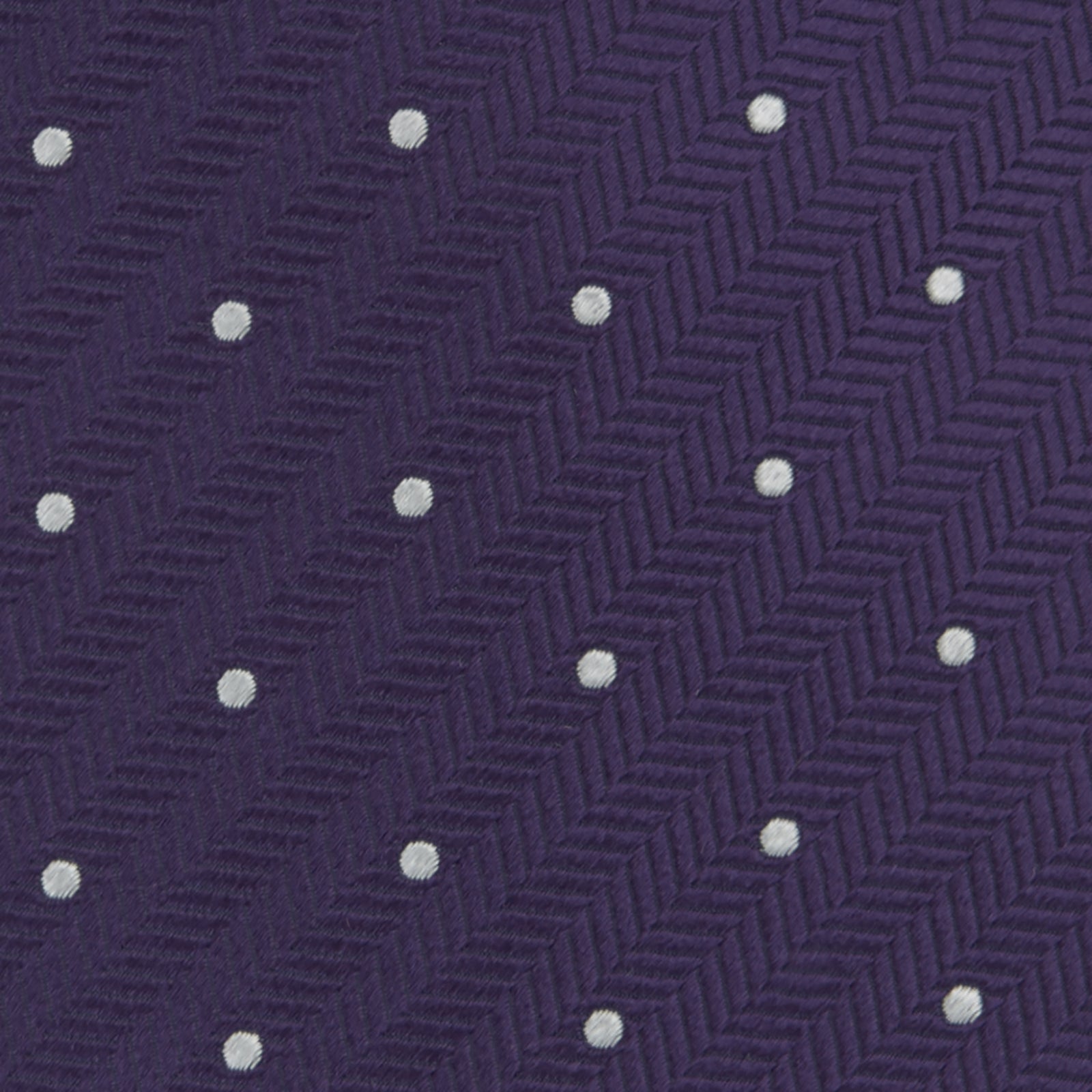 View 3 of product The Turnbull & Asser Plum and White Small Spot Herringbone Silk Tie is shown rolled up on a plain white background, featuring a classic silk herringbone weave in plum with small white spots.