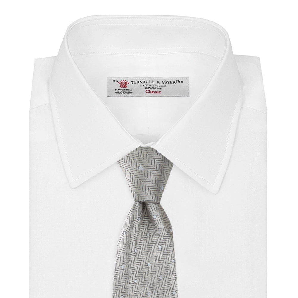 The Turnbull & Asser Silver and White Small Spot Herringbone Silk Tie features a subtle pattern of small, evenly spaced light dots and is expertly crafted from fine English silk.
