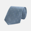 View 1 of product The Turnbull & Asser Ice Blue and White Small Spot Herringbone Silk Tie features a refined herringbone weave with subtle white spots, displayed elegantly against a plain white background.