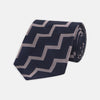 View 1 of product The Turnbull & Asser Navy and Rose Striped Zigzag Silk Tie features a bold zigzag pattern and is shown against a plain white background, making it an ideal accessory for the modern gentleman.