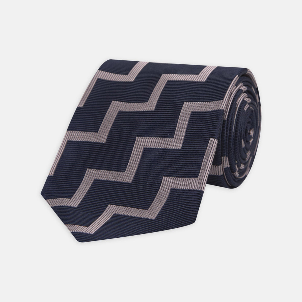 The Turnbull & Asser Navy and Rose Striped Zigzag Silk Tie features a bold zigzag pattern and is shown against a plain white background, making it an ideal accessory for the modern gentleman.