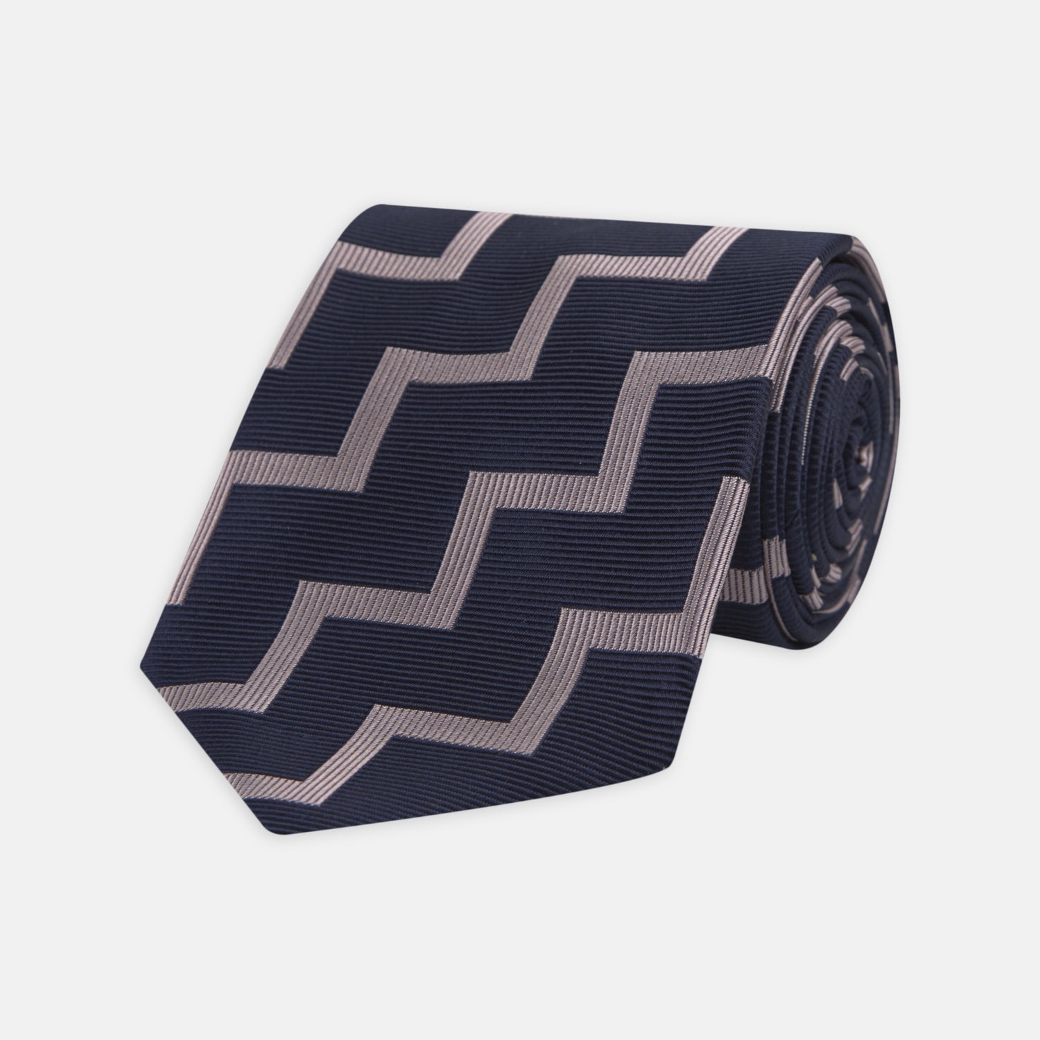 View 1 of product The Turnbull & Asser Navy and Rose Striped Zigzag Silk Tie features a bold zigzag pattern and is shown against a plain white background, making it an ideal accessory for the modern gentleman.