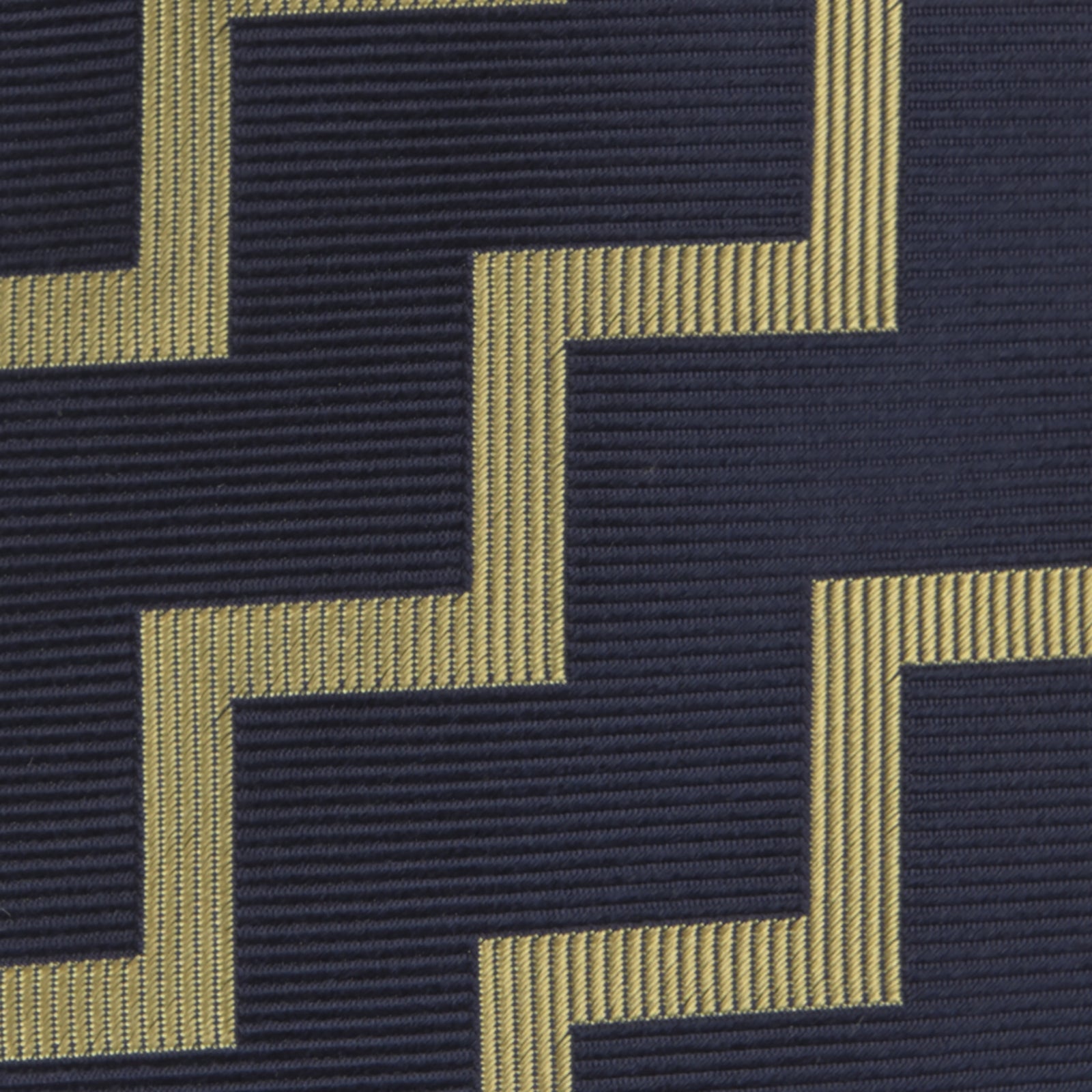 View 3 of product The Navy and Gold Striped Zigzag Silk Tie by Turnbull & Asser features a bold geometric pattern—an essential modern accessory shown rolled up with the pointed end forward on a white background.