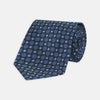 View 1 of product Turnbull & Asser’s Forest Green and Blue Circle and Spot Silk Tie, rolled on a white background, features a refined pattern—an elegant classic for any office shirt.