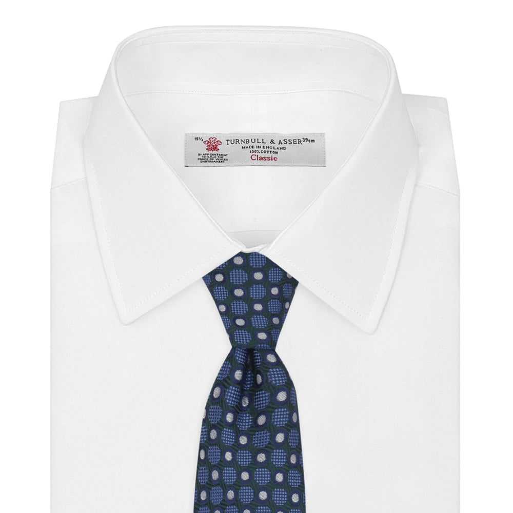 Turnbull & Asser’s Forest Green and Blue Circle and Spot Silk Tie, rolled on a white background, features a refined pattern—an elegant classic for any office shirt.