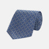 View 1 of product The Turnbull & Asser Blue Circle and Spot Silk Tie features a refined pattern of light blue and silver circles—ideal for pairing with an office shirt, elegantly displayed rolled on a plain white background.