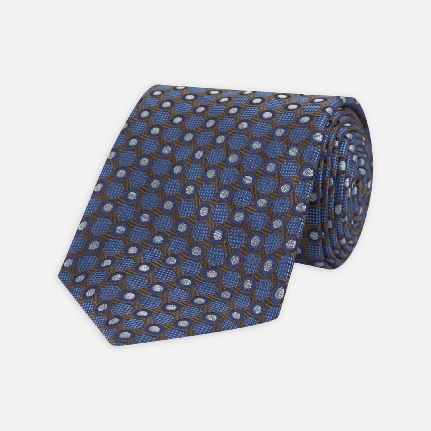 View 1 of product The Turnbull & Asser Brown and Blue Circle and Spot Silk Tie features a repeating pattern of brown and blue spots, ideal for office wear, shown on a white background.