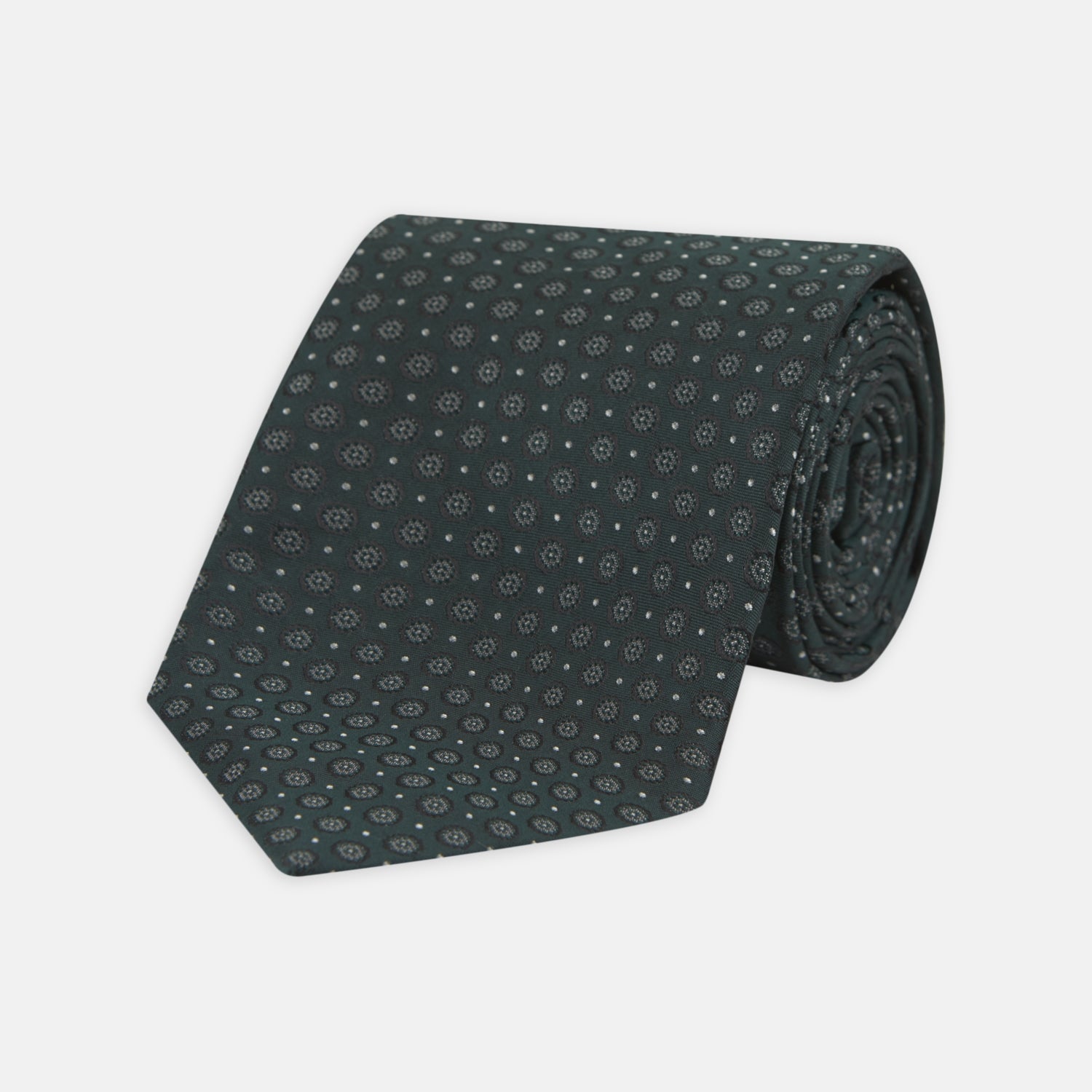 View 1 of product The Turnbull & Asser Forest Green Floral Spot Silk Tie features a subtle light gray circular pattern, shown rolled on a white background—a classic accessory ideal for office shirts.