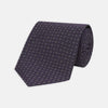 View 1 of product The Turnbull & Asser Plum Floral Spot Silk Tie features a rolled-up classic design with small, evenly spaced floral spots in lighter purple and white, ideal for office shirts and shown against a plain white background.