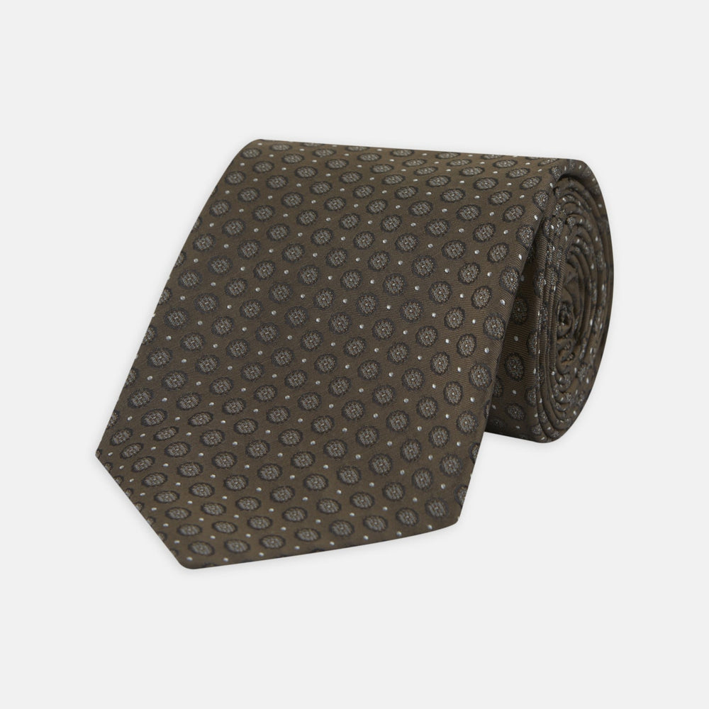 The Brown Floral Spot Silk Tie by Turnbull & Asser features a classic brown base with silver-gray floral spots—an elegant accessory that pairs perfectly with your office shirts.