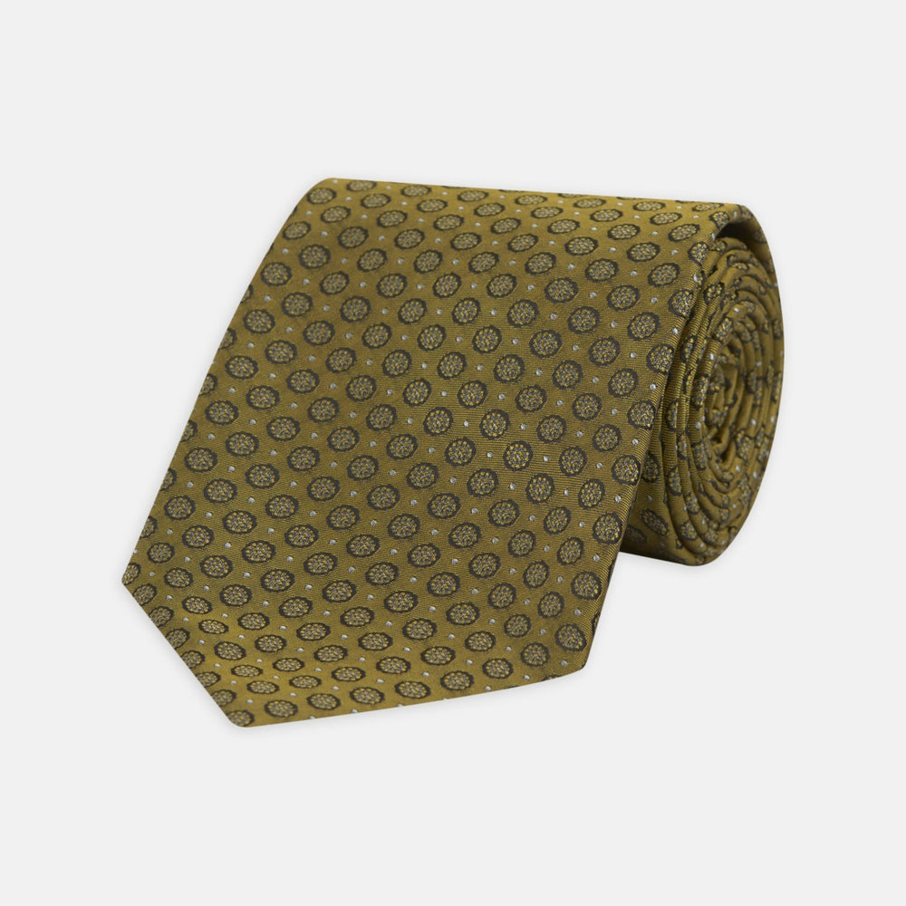 The Gold Floral Spot Silk Tie by Turnbull & Asser showcases a rolled-up design in olive green silk with light floral spots, perfect for adding a refined touch to any office shirt and standing out against a plain white background.