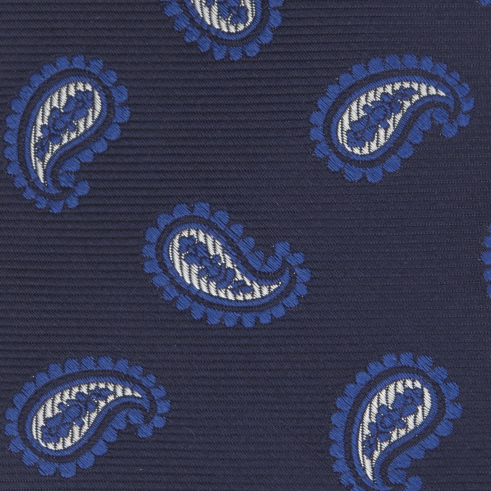 View 3 of product The Turnbull & Asser Navy and Royal Blue Floating Paisley Silk Tie features an elegant blue and white paisley pattern, styled in a rolled presentation on a plain white background.