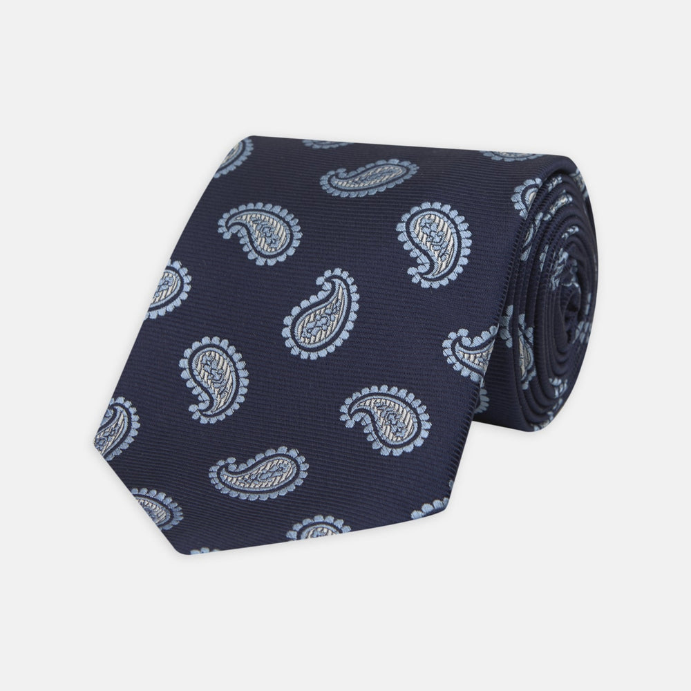 The Turnbull & Asser Navy and Light Blue Floating Paisley Silk Tie features a repeating light blue and white paisley pattern set against a navy blue silk backdrop.