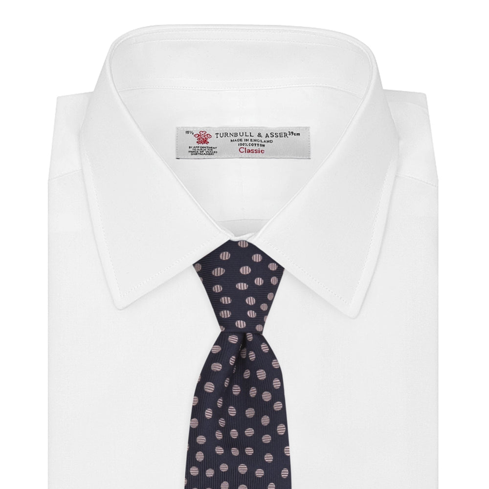 The Turnbull & Asser Navy and Pink Paint Spot Silk Tie, rolled at one end and set against a white background, adds a stylish touch to any office shirt with its modern spot pattern.