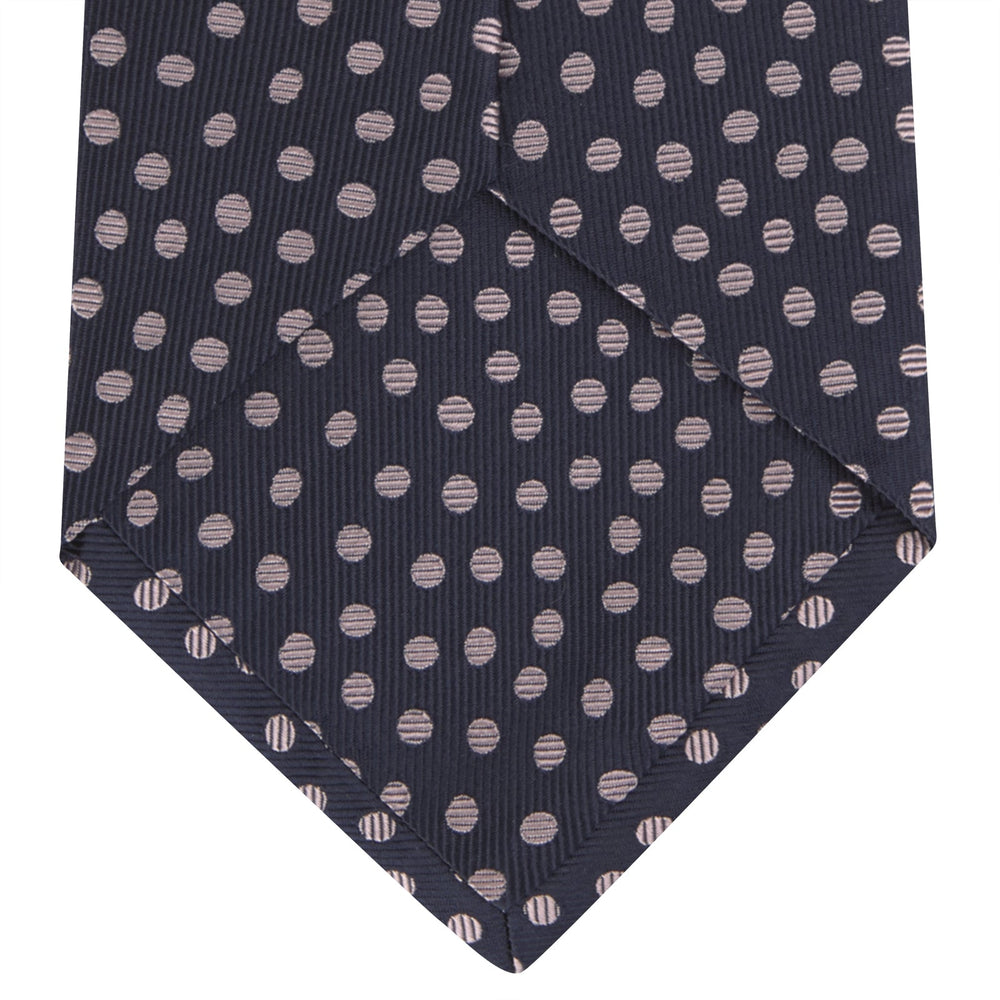 The Turnbull & Asser Navy and Pink Paint Spot Silk Tie, rolled at one end and set against a white background, adds a stylish touch to any office shirt with its modern spot pattern.
