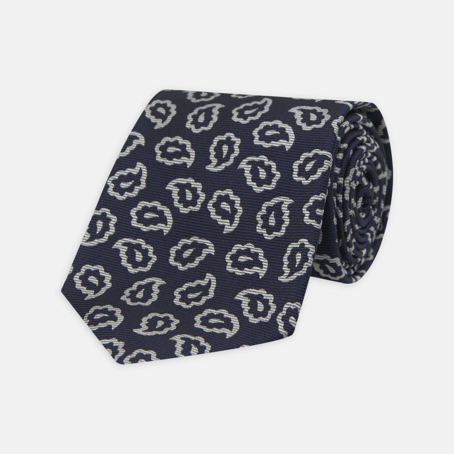 View 1 of product The Turnbull & Asser Navy and White Petal Paisley Silk Tie, featuring an elegant abstract pattern, is neatly rolled against a plain white background.