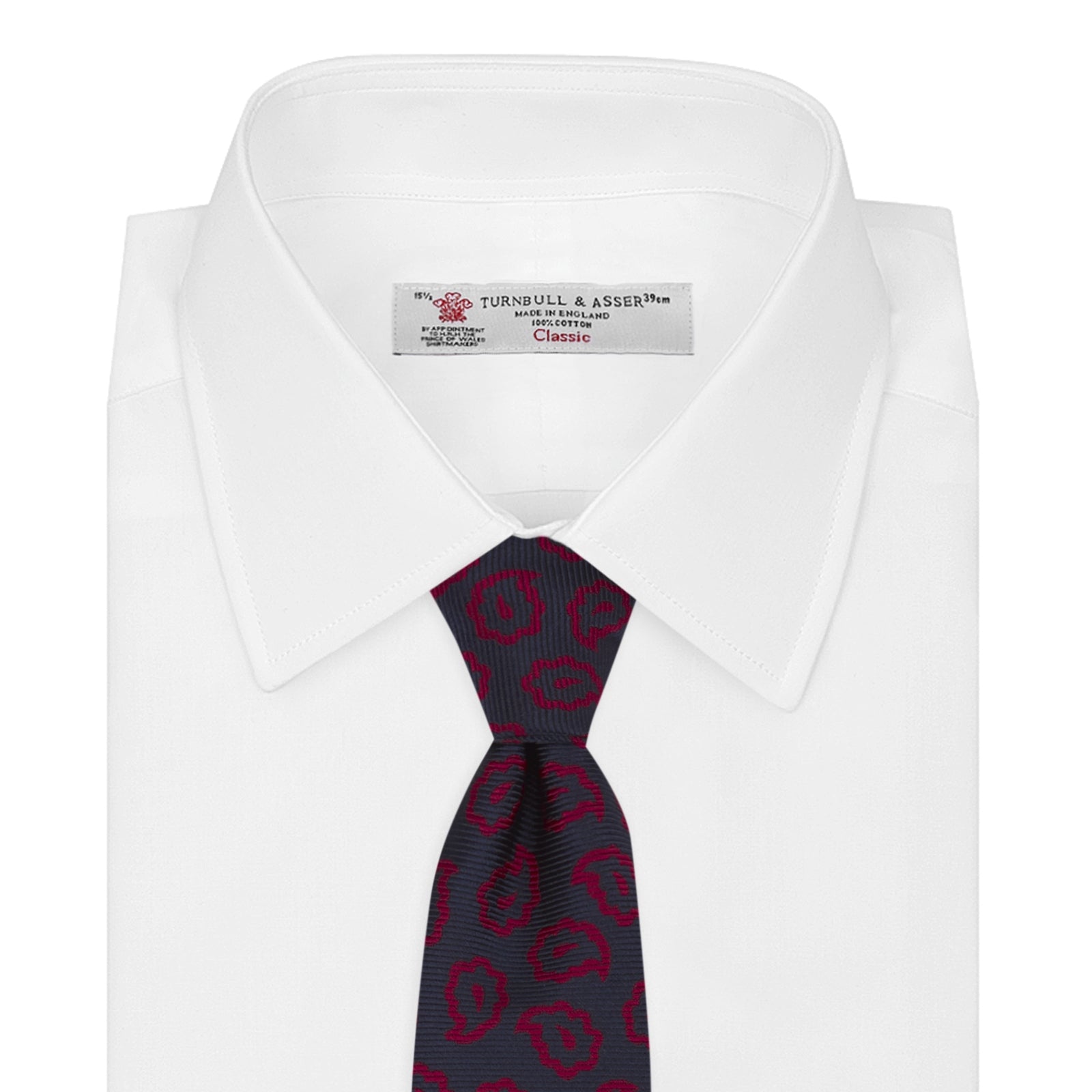 View 2 of product The Navy and Red Petal Paisley Silk Tie by Turnbull & Asser features an elegant paisley pattern on navy silk, rolled at one end and displayed on a plain white background.
