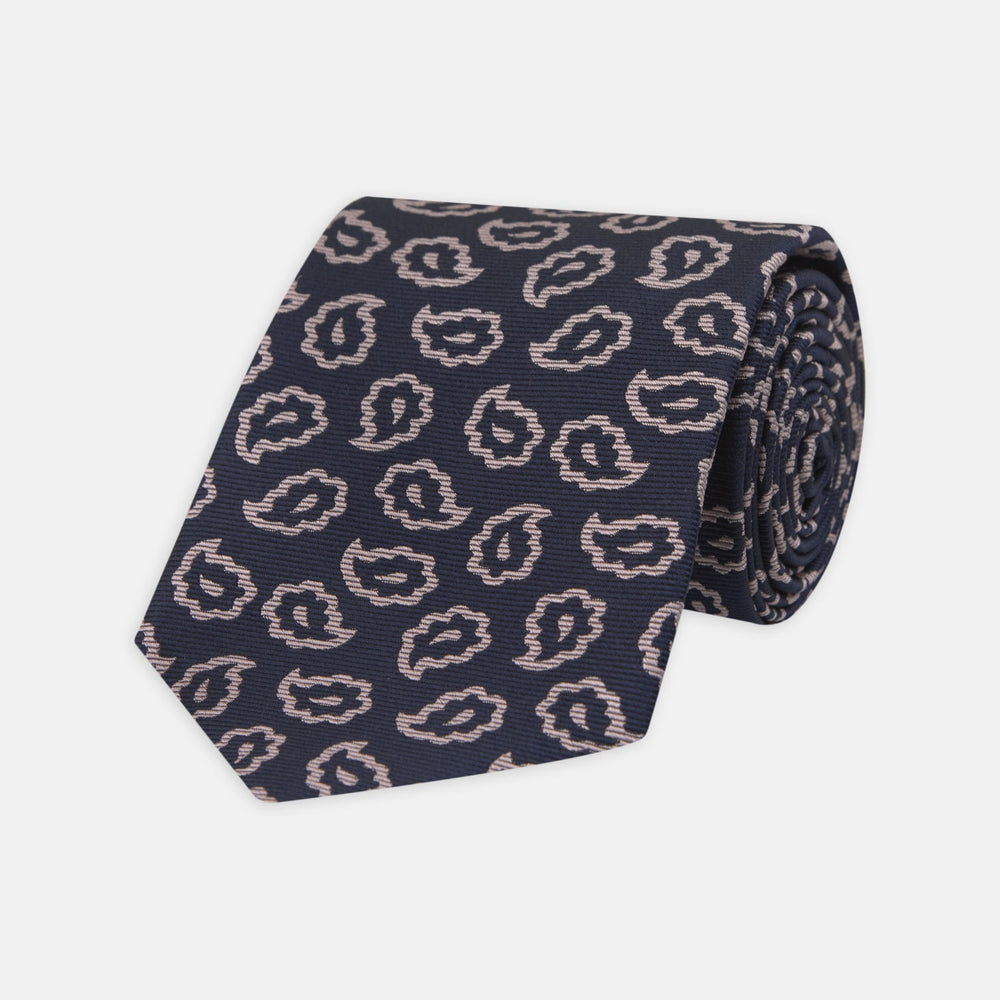 The Turnbull & Asser Navy and Pink Petal Paisley Silk Tie features a repeating petal paisley pattern in pink, shown rolled with the pointed end forward against a plain white background.