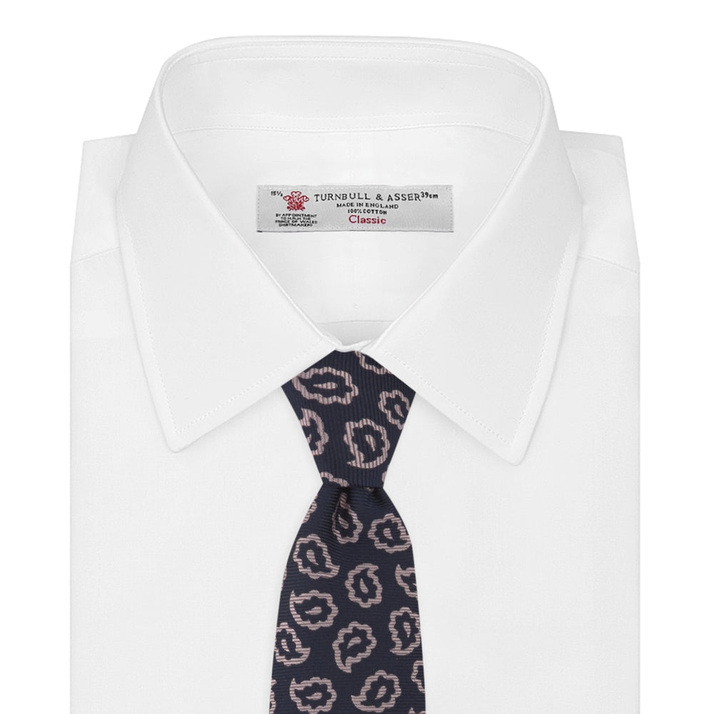 The Turnbull & Asser Navy and Pink Petal Paisley Silk Tie features a repeating petal paisley pattern in pink, shown rolled with the pointed end forward against a plain white background.