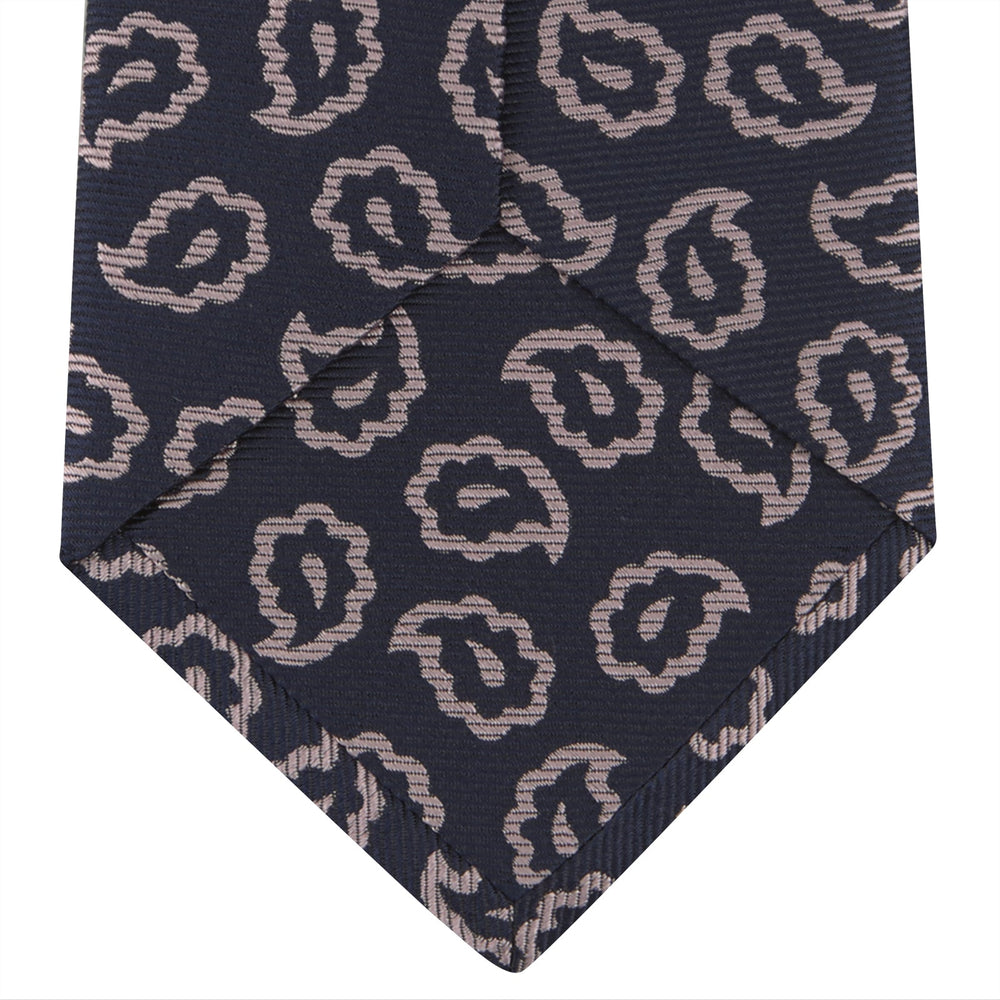 The Turnbull & Asser Navy and Pink Petal Paisley Silk Tie features a repeating petal paisley pattern in pink, shown rolled with the pointed end forward against a plain white background.