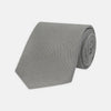 View 1 of product The Turnbull & Asser Light Grey Grenadine Silk Tie features a finely textured checkered pattern and superb dimensional stability, shown rolled up against a plain white background.