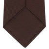 View 4 of product The Turnbull & Asser Burgundy Grenadine Silk Tie, featuring a textured grenadine weave, is rolled up and displayed against a plain white background.