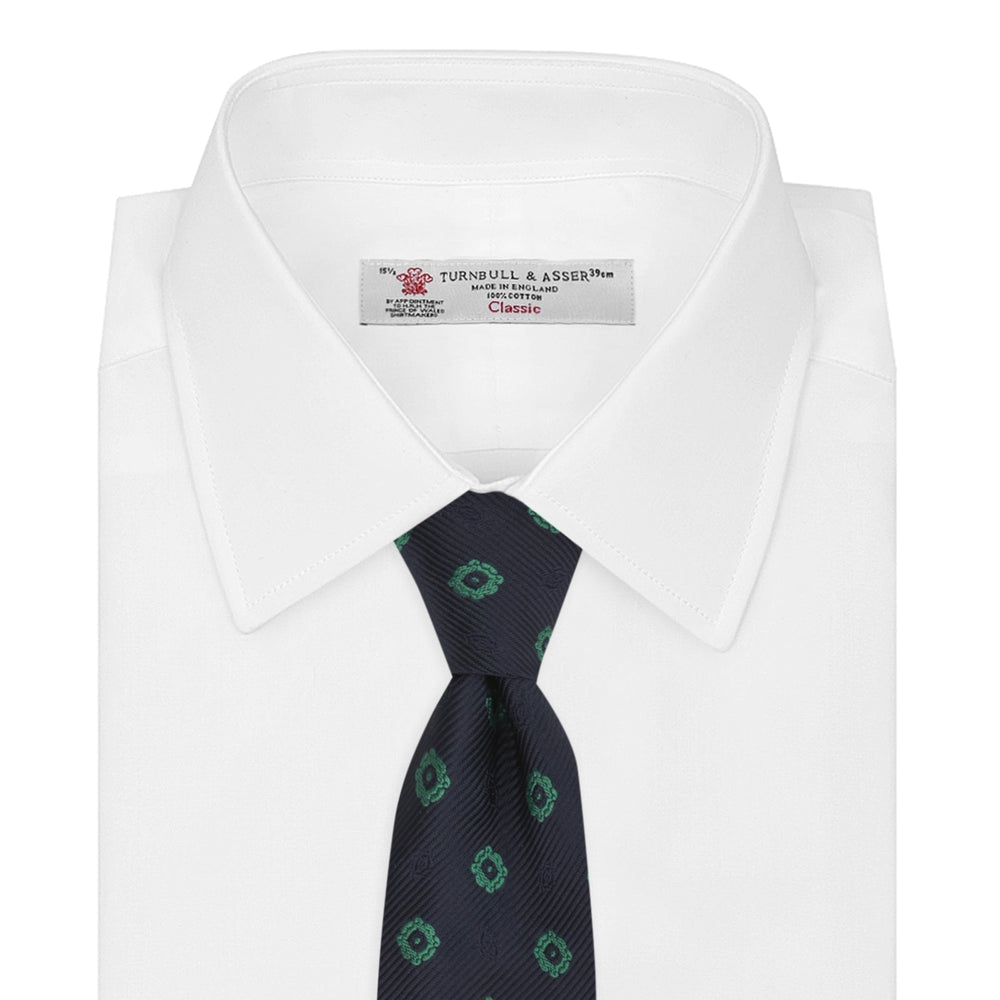 The Navy and Green Emblem Spot Silk Tie by Turnbull & Asser features a classic dark navy base with small green motif spots—perfect for adding a refined touch to your favorite office shirt.