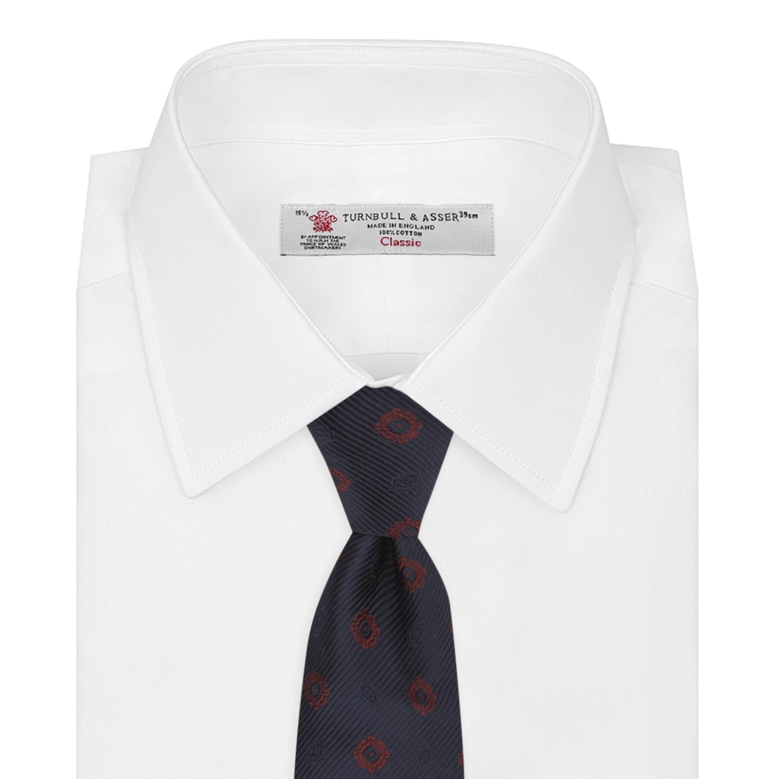 View 2 of product The Turnbull & Asser Navy and Burgundy Emblem Spot Silk Tie features a subtle textured pattern with small burgundy emblems on navy silk. Perfectly rolled with a pointed tip, it pairs well with any office shirt.
