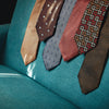 View 6 of product The Turnbull & Asser Tomorrow Never Dies Diamond Silk Tie, as seen on James Bond, features a gold and navy checkered pattern—an ideal gift for any Bond fan. Displayed rolled against a plain white background.