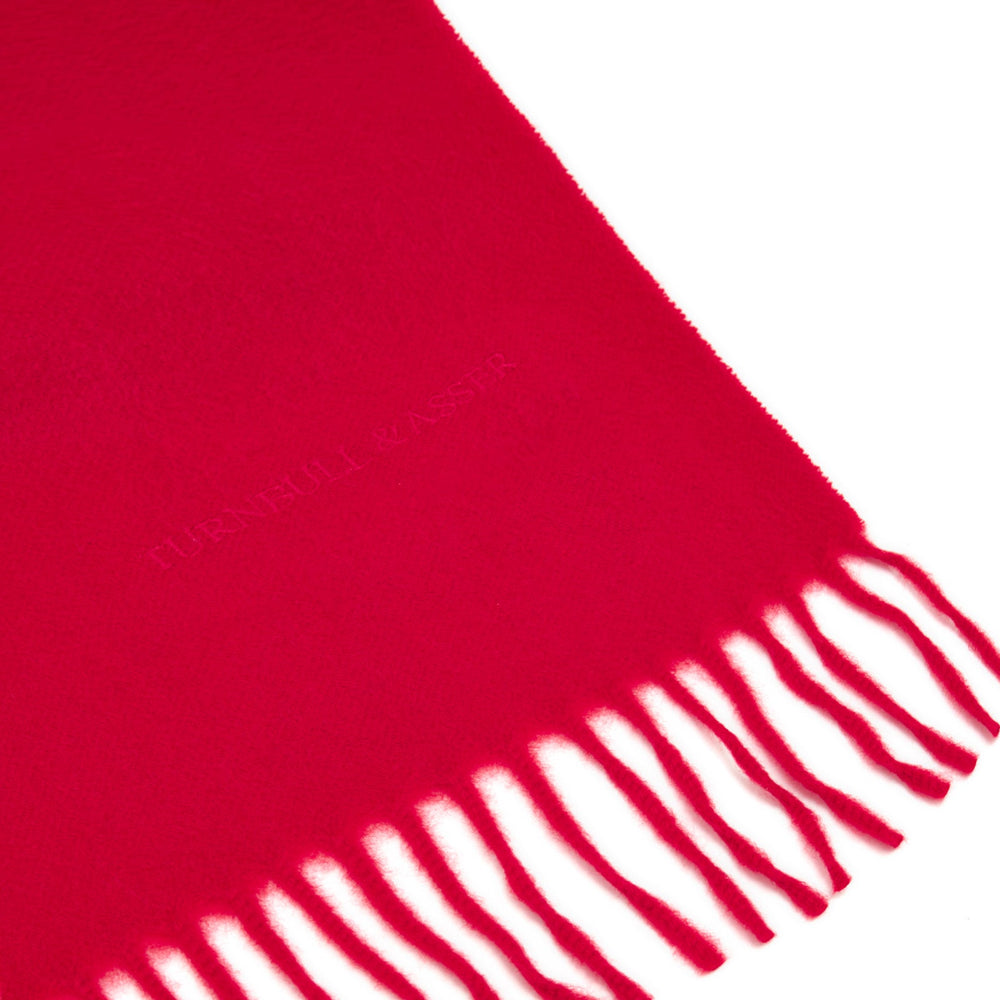 The Turnbull & Asser Red Pure Cashmere Scarf features hand-woven cashmere with fringed ends, elegantly folded against a plain white background for a classic Scottish look.
