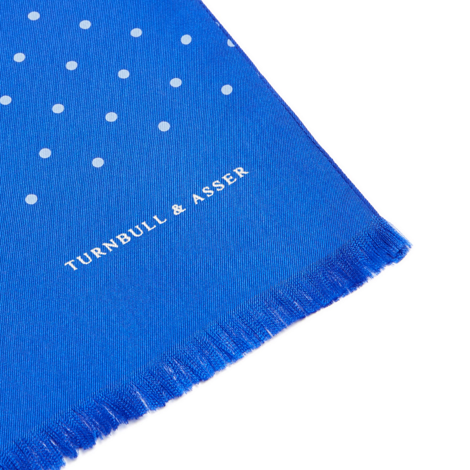 View 2 of product The Turnbull & Asser Royal Blue and White Spotted Silk Scarf features a soft silk fabric, short fringes at both ends, neatly folded center, and a hand-printed polka dot design for a distinctive, elegant look.