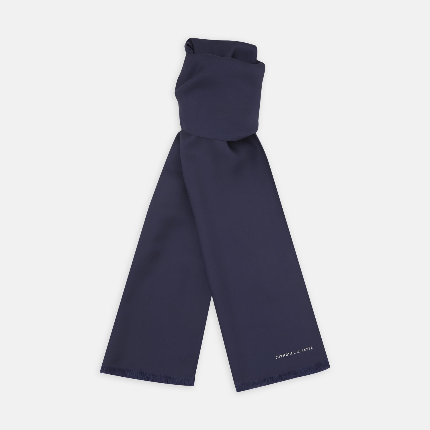 View 1 of product A Plain Navy Silk Scarf by Turnbull & Asser, neatly folded with both ends hanging down, is shown against a white background. One end displays subtle white branding, highlighting this elegant accessory.