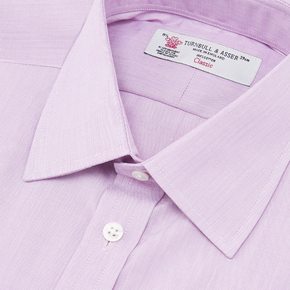 A neatly folded Turnbull & Asser Lilac End-on-End Shirt with T&A collar and 3-button cuffs, featuring white buttons and long sleeves, is displayed on a plain white background.