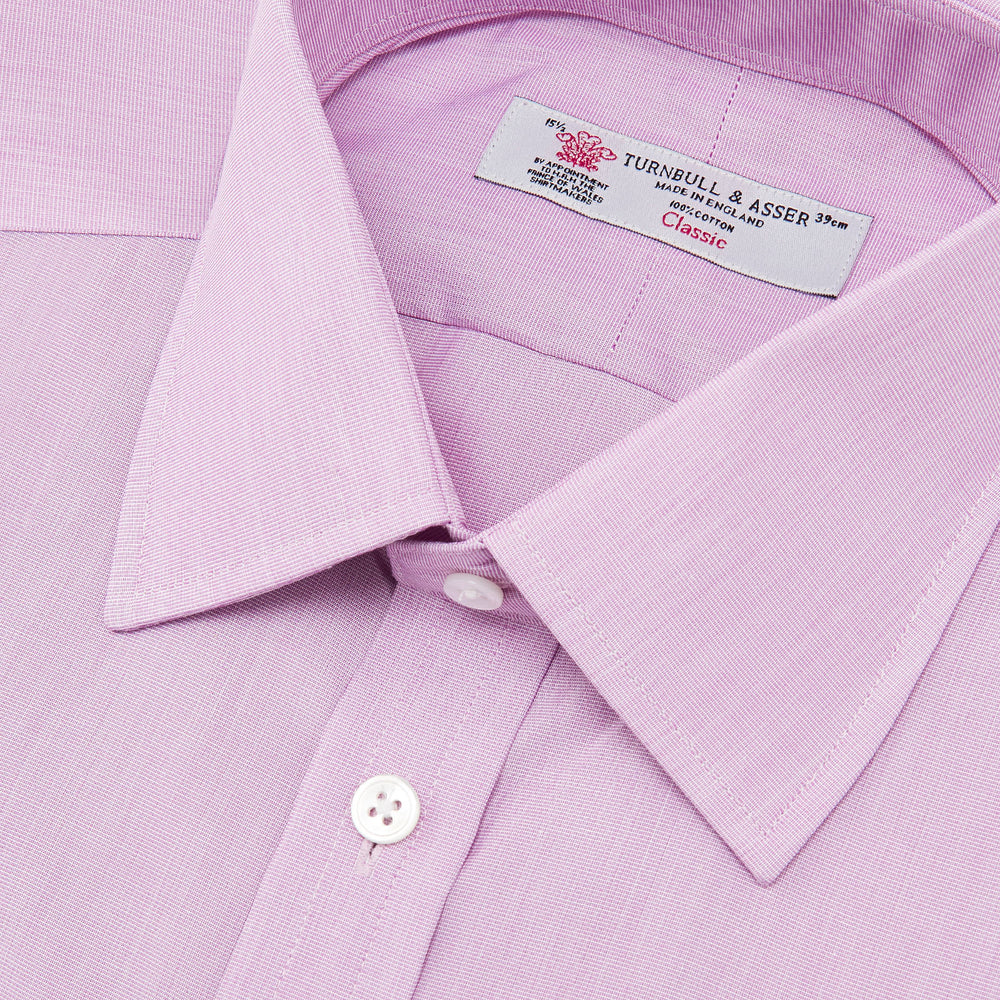 The Turnbull & Asser Lilac End-on-End Shirt features a T&A collar, double cuffs, and white buttons. Crafted from Italian two-tone cloth, this long-sleeved shirt is neatly folded and displayed on a plain white background.