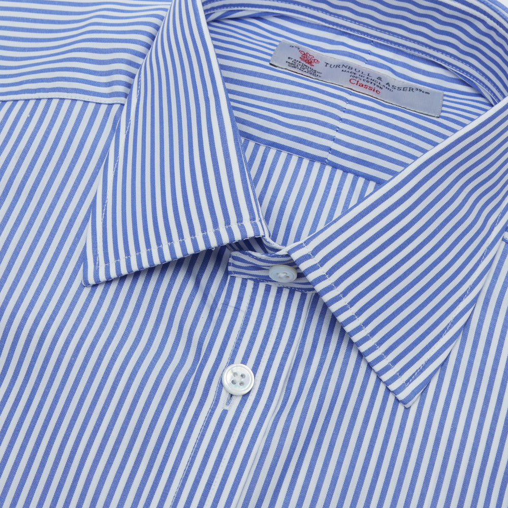 The Turnbull & Asser Blue Bengal Stripe Shirt features a T&A collar, double cuffs, and crisp white buttons. Made from cotton with blue and white bengal stripes, it’s neatly folded and displayed on a white background.