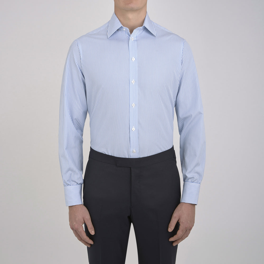 The Turnbull & Asser Light Blue Bengal Stripe Shirt features a T&A collar, double cuffs, and white buttons, offering British flair in blue and white stripes against a plain background.