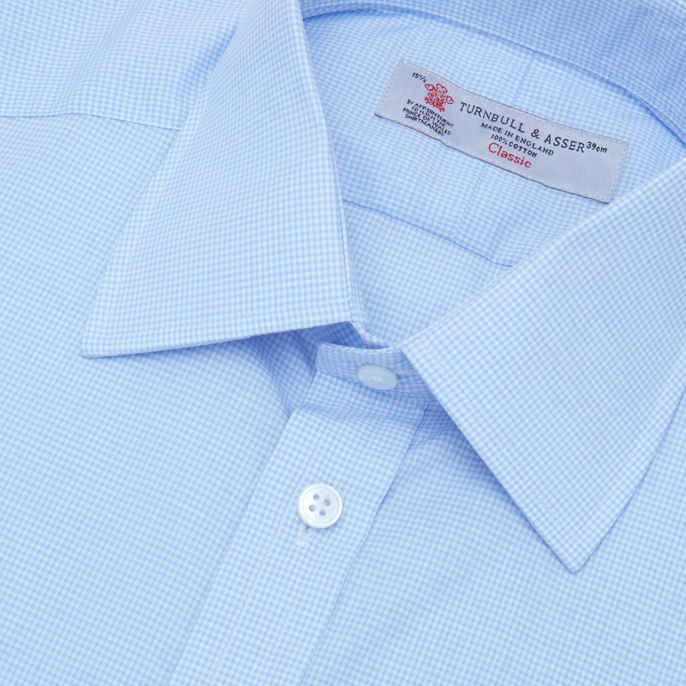 The Sky Blue Micro-Check Cotton Shirt by Turnbull & Asser features a T&A collar and 3-button cuffs, offering a refined take on classic British style. The shirt is neatly folded, showcasing its signature elegance against a white background.