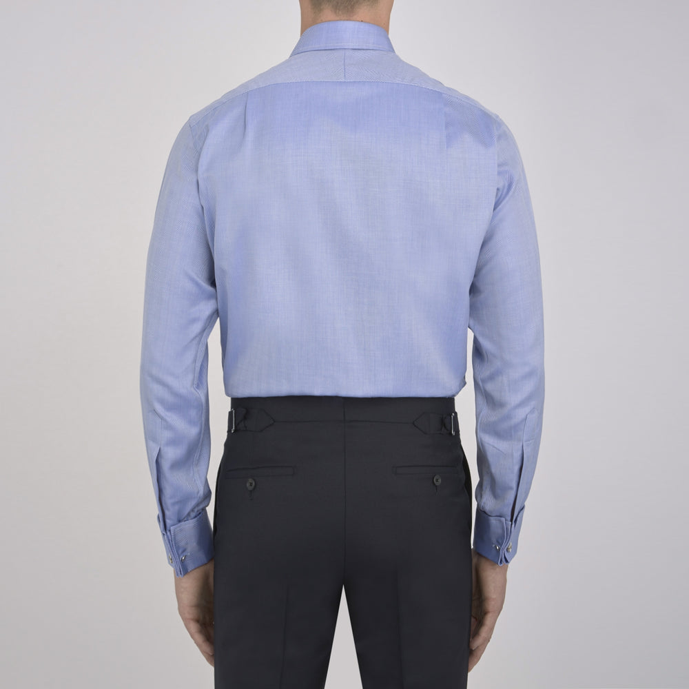 The Turnbull & Asser Blue Herringbone Superfine Cotton Shirt features a T&A collar and double cuffs—an essential for discerning gentlemen—shown folded on a plain white background.