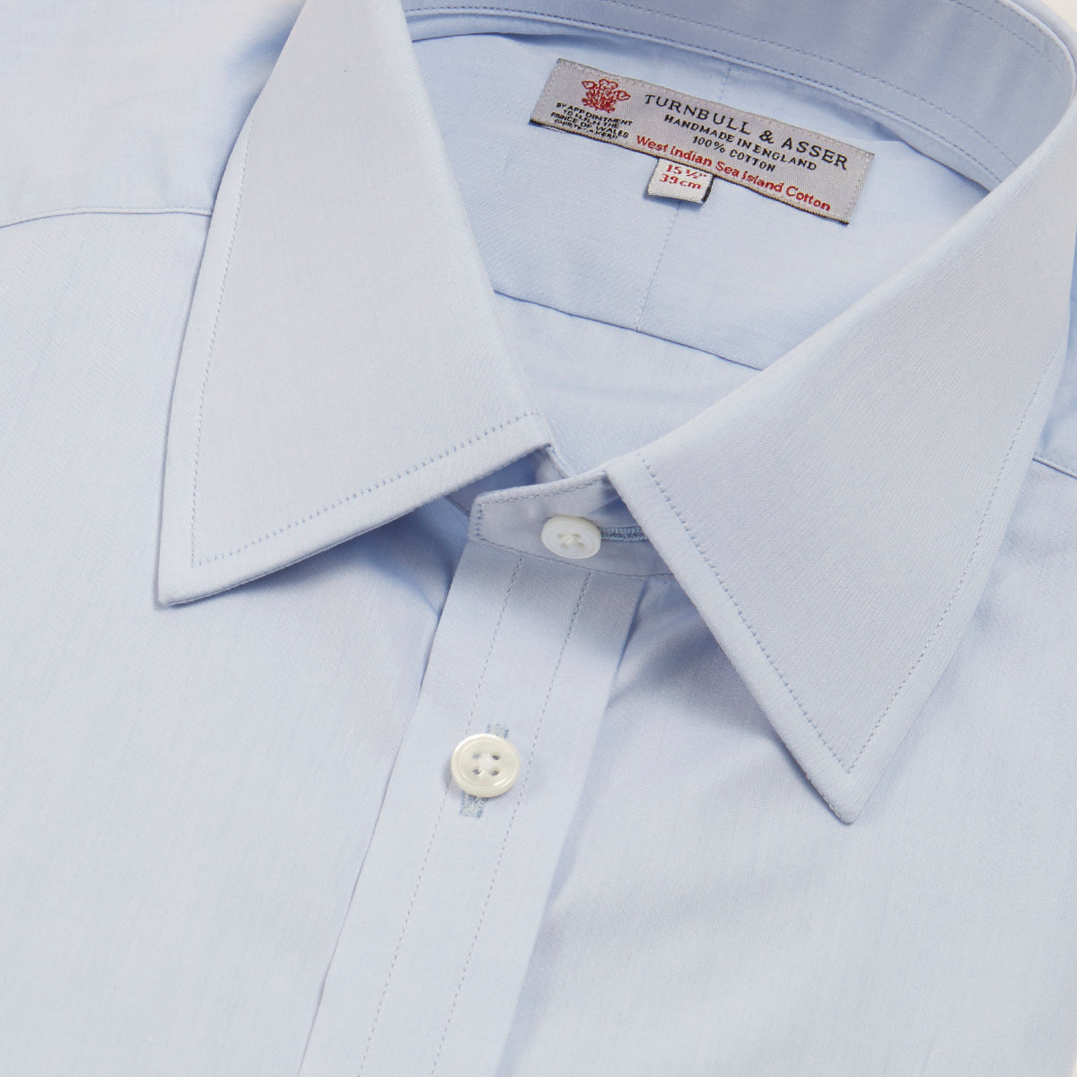 View 5 of product A neatly folded light blue long-sleeve dress shirt with a pointed collar and white buttons, styled with the Turnbull & Asser Monochrome Paisley Mill Silk Pocket Square (limited edition), displayed against a plain white background.