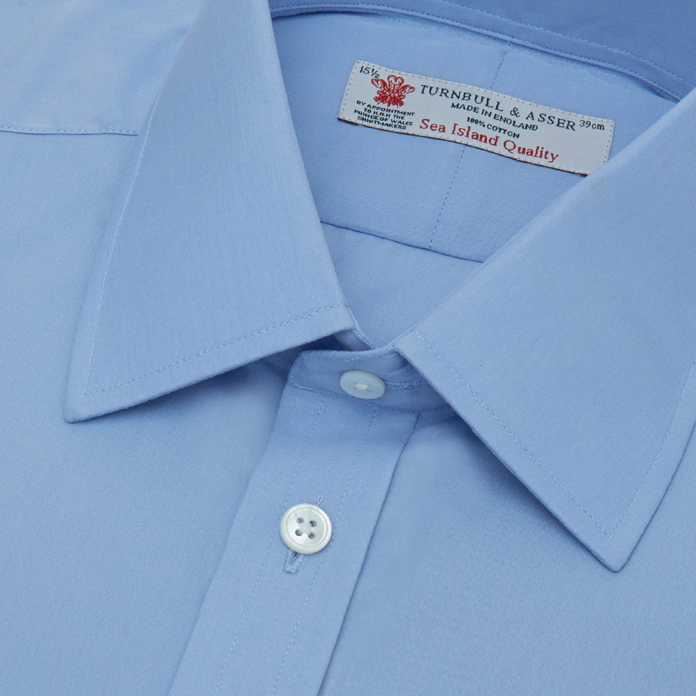 The Turnbull & Asser Blue Sea Island Quality Cotton Shirt features a T&A collar, double cuffs, and is showcased neatly folded on a plain white background.