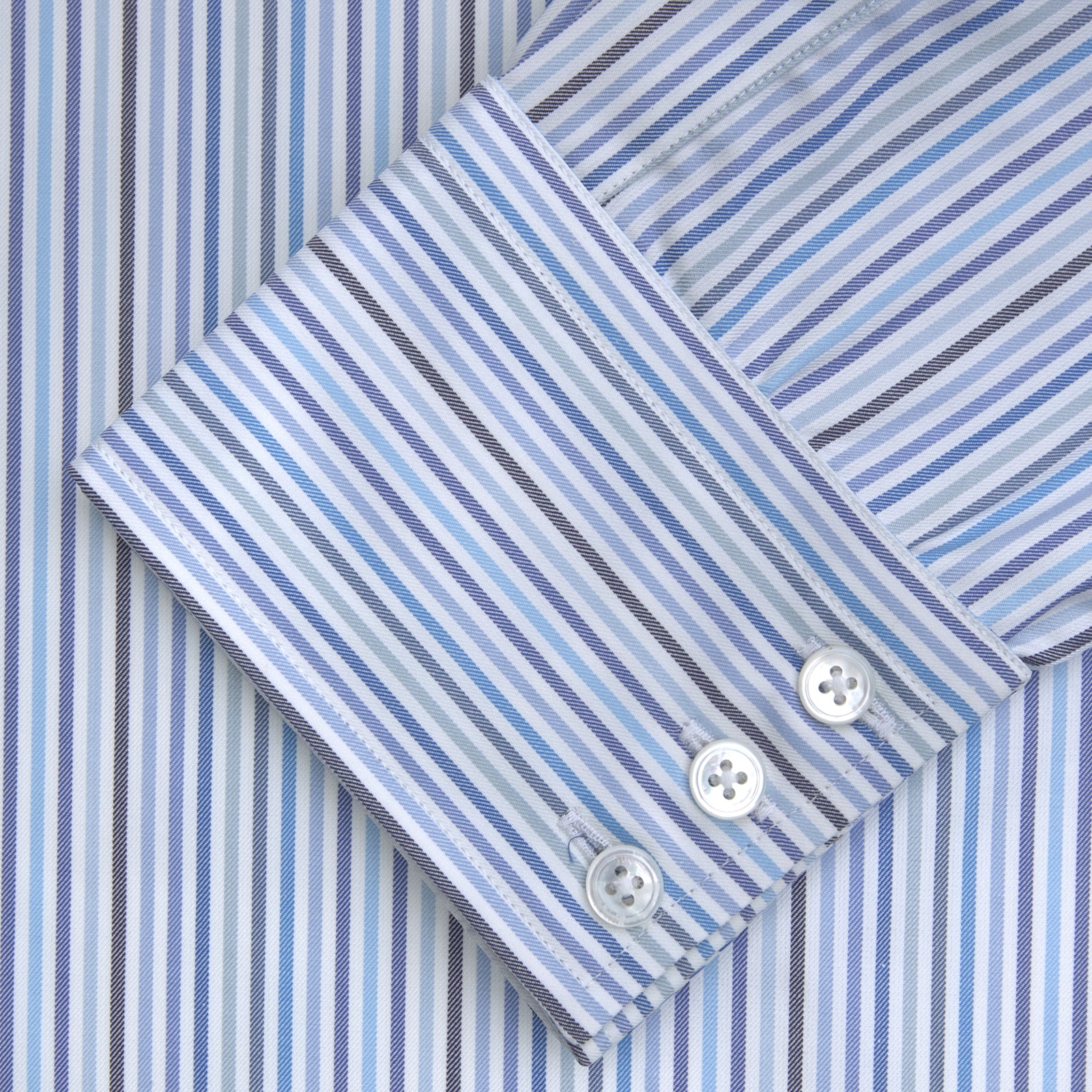 View 2 of product The Turnbull & Asser Blue and White Graph Stripe Shirt features a T&A collar, 3-button cuffs, and crisp vertical stripes, exemplifying refined bespoke tailoring. Displayed neatly folded on a plain light background.