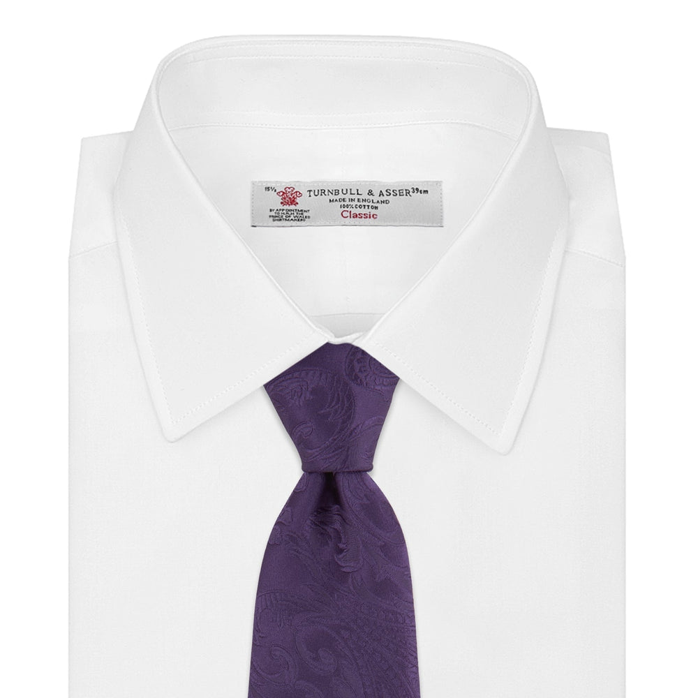 The Turnbull & Asser Purple Paisley Silk Tie, shown rolled on a white background, features an elegant paisley design—a stylish statement piece for any occasion.
